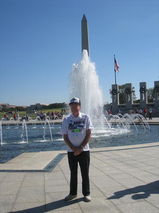 WW II Veteran Hero Bill Taylor stands at the center of the World War II Memorial while taking in the whole experience of finally getting the opportunity to visit his memorial with the Washington Monument in the background.